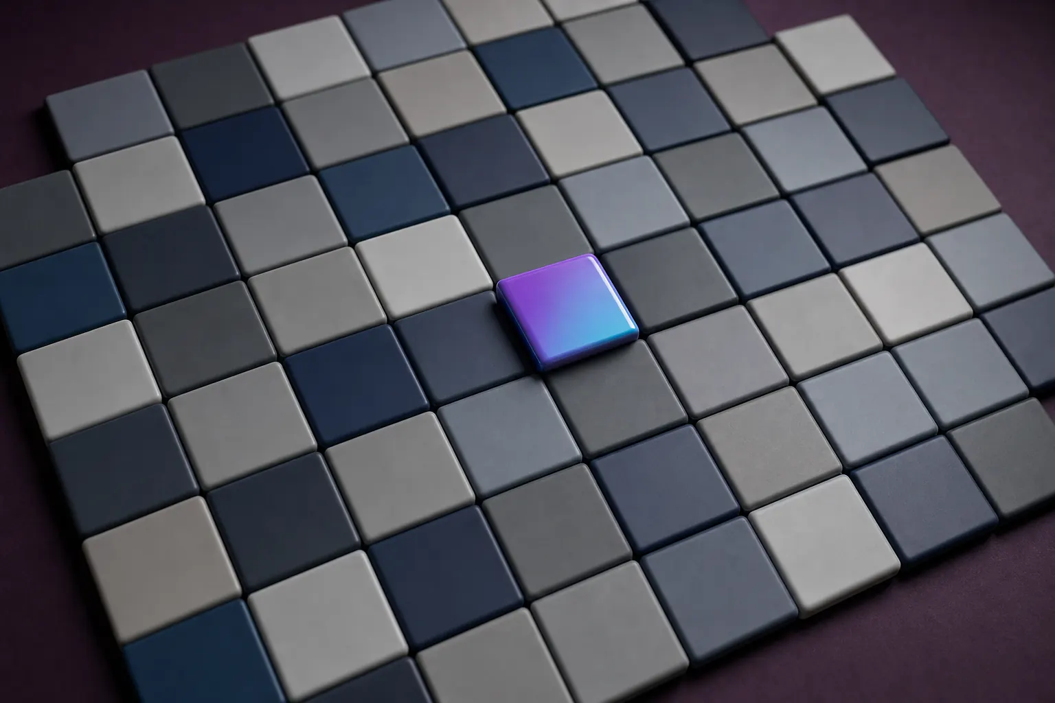 Grid of blank matte grey and navy tiles seen from above with one glossy violet and cyan gradient tile raised in the centre